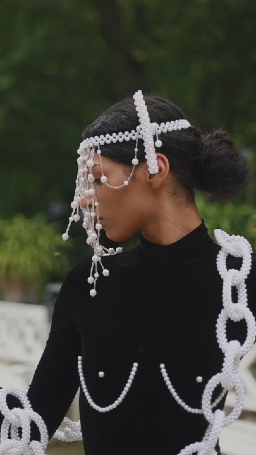 Load video: elderly dark skinned woman wearing a red beaded, pearl headpiece